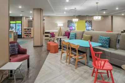 a waiting room with a couch and tables and chairs at Home2 Suites By Hilton Dayton Centerville in Centerville