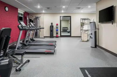 a gym with cardio equipment and a red wall at Home2 Suites By Hilton Dayton Centerville in Centerville