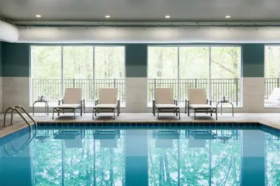 a pool in a hotel with chairs and tables and windows at Holiday Inn Express & Suites - Millersburg by IHG in Millersburg
