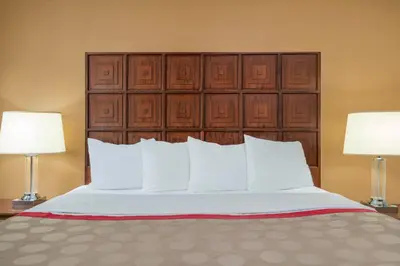 a bed with white pillows and two lamps at Ramada by Wyndham Columbus North in Westerville