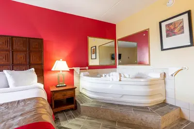 a bedroom with a large bathtub with a large mirror at Ramada by Wyndham Columbus North in Westerville