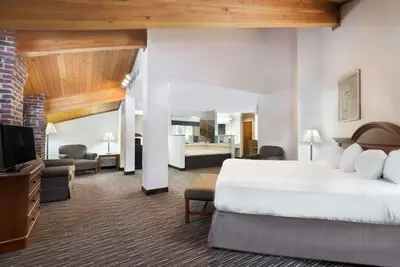 a hotel room with a bed and a living room at Baymont by Wyndham Columbus/Rickenbacker in Columbus
