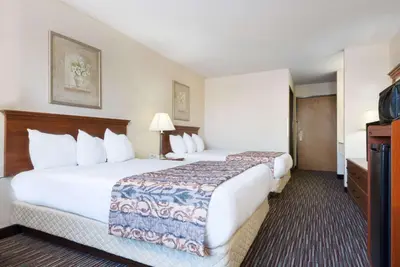 a hotel room with two beds and a television at Baymont by Wyndham Columbus/Rickenbacker in Columbus