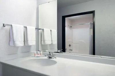 a white bathroom with a sink and a mirror at Baymont by Wyndham Columbus/Rickenbacker in Columbus