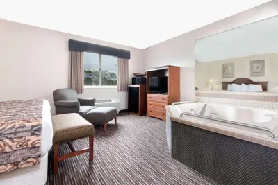 a hotel room with a bed and a bathtub and a bedroom at Baymont by Wyndham Columbus/Rickenbacker in Columbus