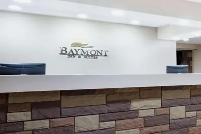 a reception desk with a logo on a wall at Baymont by Wyndham Columbus/Rickenbacker in Columbus