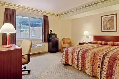 a hotel room with a bed and a desk and chair at Days Inn by Wyndham Cleveland Lakewood in Lakewood