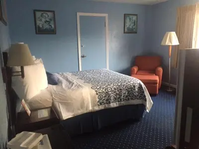 a hotel room with a bed and a chair at Days Inn by Wyndham Cleveland Lakewood in Lakewood