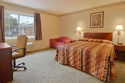 a hotel room with a bed and a desk and a chair at Days Inn by Wyndham Cleveland Lakewood in Lakewood
