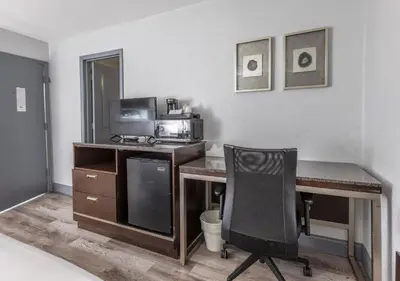 a room with a desk with a microwave and a chair at Butler Inn in Oxford