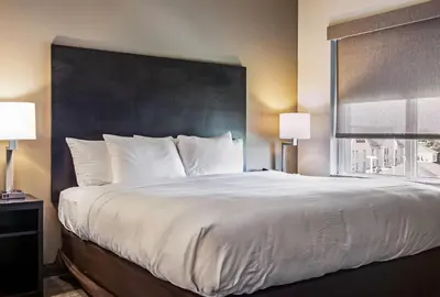 a large bed with white sheets and a large window at Comfort Suites Wooster near University Campus in Wooster