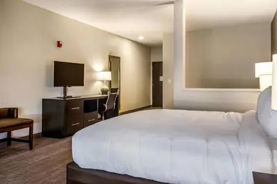 a hotel room with a large white bed and a desk at Comfort Suites Brunswick Town Center in Brunswick