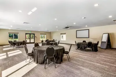 a conference room with tables and chairs and a screen at Comfort Suites Brunswick Town Center in Brunswick