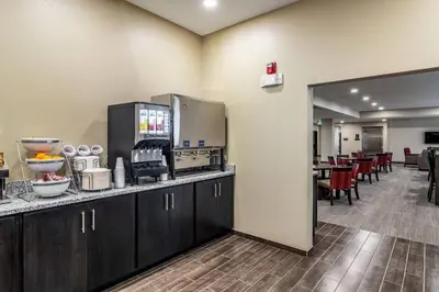 a kitchen with a counter and a cafeteria with tables at Comfort Suites Brunswick Town Center in Brunswick