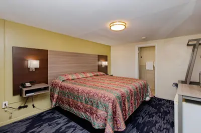a hotel room with a bed and a bathroom at Budget Inn Columbus in Lockbourne