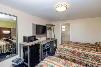 a hotel room with two beds and a desk at Budget Inn Columbus in Lockbourne
