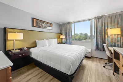 a hotel room with a bed and a desk and a window at Suburban Studios Fairborn - Dayton in Fairborn