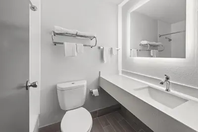 a bathroom with a toilet and a sink and a mirror at Suburban Studios Fairborn - Dayton in Fairborn