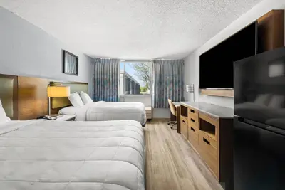 a hotel room with two beds and a flat screen tv at Suburban Studios Fairborn - Dayton in Fairborn