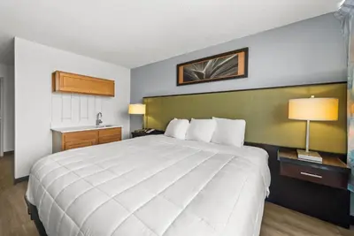a large white bed in a hotel room at Suburban Studios Fairborn - Dayton in Fairborn
