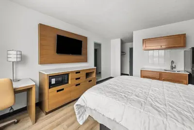 a bedroom with a bed and a flat screen tv at Suburban Studios Fairborn - Dayton in Fairborn