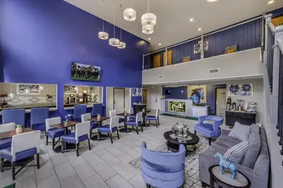 a lobby with blue chairs and tables at Guesthouse Inn & Suites Lexington in Lexington