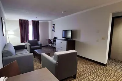 a hotel room with a couch and chairs and a television at Wingate by Wyndham Canton-Hall of Fame in Canton
