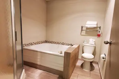 a bathroom with a bath tub and a toilet at Wingate by Wyndham Canton-Hall of Fame in Canton