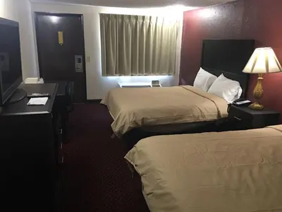 a hotel room with two beds and a desk with a lamp at Super 9 Motel Troy in Troy