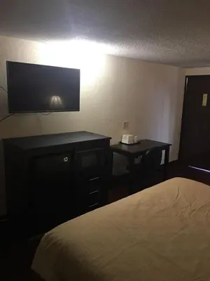 a hotel room with a bed and a desk with a television at Super 9 Motel Troy in Troy