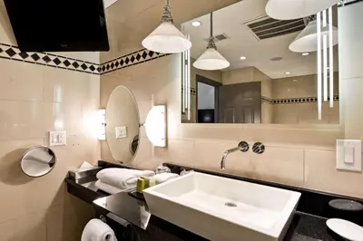 a bathroom with a sink and a mirror at The Cincinnatian Curio Collection by Hilton in Cincinnati