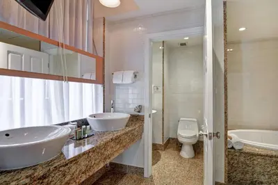 a bathroom with two sinks and a tub and a toilet at The Cincinnatian Curio Collection by Hilton in Cincinnati