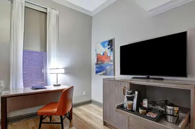 a living room with a flat screen tv and a chair at The Cincinnatian Curio Collection by Hilton in Cincinnati