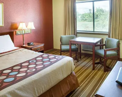 a hotel room with a bed and a table and chairs at Rodeway Inn Florence - Cincinnati South in Florence