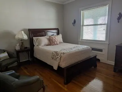 a bedroom with a bed and a chair and a window at Farrell House Lodge at Sunnybrook Trout Club in Sandusky