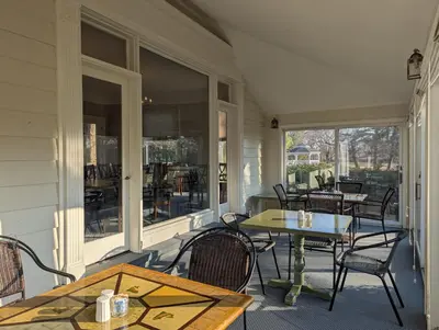 a porch with a table and chairs and a table andwindows at Farrell House Lodge at Sunnybrook Trout Club in Sandusky