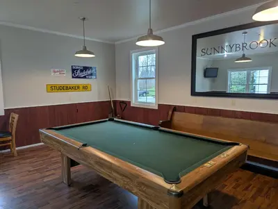a billiard room with a pool table and benches at Farrell House Lodge at Sunnybrook Trout Club in Sandusky