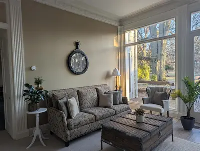 a living room with a couch and a clock on the wall at Farrell House Lodge at Sunnybrook Trout Club in Sandusky
