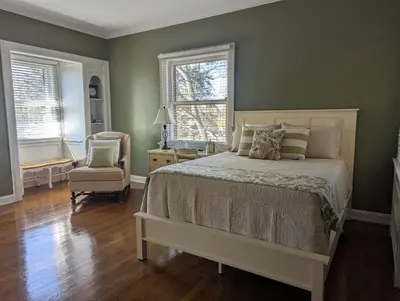 a bedroom with a bed and a chair and windows at Farrell House Lodge at Sunnybrook Trout Club in Sandusky