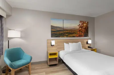 a bedroom with a bed and a blue chair at Days Inn by Wyndham Charleston WV in Charleston