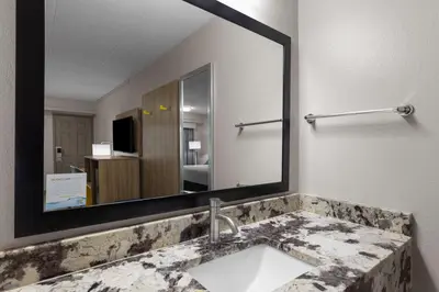a bathroom with a sink and a large mirror at Days Inn by Wyndham Charleston WV in Charleston