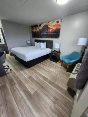 a bedroom with a bed and a blue chair at Days Inn by Wyndham Charleston WV in Charleston