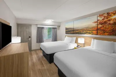 a hotel room with two beds and a flat screen tv at Days Inn by Wyndham Charleston WV in Charleston
