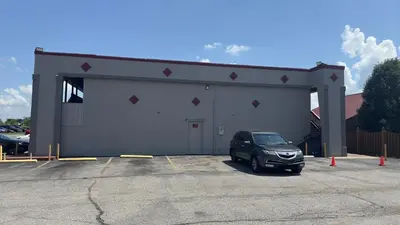 a car parked in front of a large building at Red Roof Inn Anderson, IN in Anderson