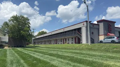 a building with a grass field in front of it at Red Roof Inn Anderson, IN in Anderson