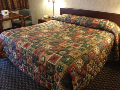 a bed in a hotel room with a colorful quilt at Richmond Inn and Suites in Richmond
