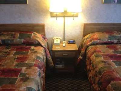 a hotel room with two beds and a night stand at Richmond Inn and Suites in Richmond