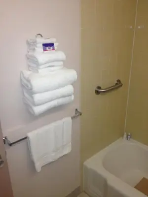 a bathroom with a stack of towels and a tub at Richmond Inn and Suites in Richmond