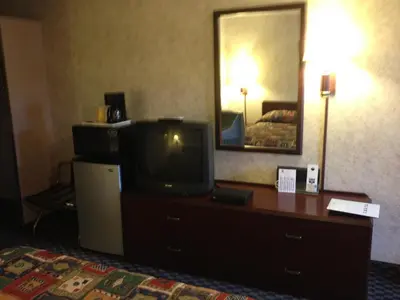 a hotel room with a television on a dresser with a bed at Richmond Inn and Suites in Richmond
