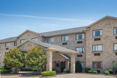 a large brick building with a tree in front of it at Ramada by Wyndham Catlettsburg Ashland in Catlettsburg